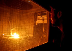 David Beltran watches as flames devour a set of cables in the SATURNE facility (IRSN) at CEA-Cadarache. Note the small blue lamp in the lower left corner of the image. (Click to view larger version...)